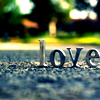 mjules: Small metal letters spelling "Love" on asphalt with sunlight and shadows. (Lovewords)