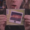 heuradys: joe dick from hard core logo holding up a cd - cover of cd has a polaroid photo of a sunset and the letter H (cd cover)
