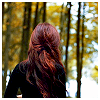 crimson_lily: Backshot image of a woman with dark red hair highlighted with copper in a black sweater, looking at dark woods (Me)