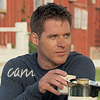 abyssinia: Cam sitting in front of barn, holding mug of tea, words "Cam" (SG1 - Cam kicks back)