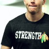 puckling: Patrick Kane's chest in a dark grey t-shirt with the word "Strength" followed by the Hawks' feathers (Strength)