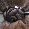 cme: Medium brown hair gathered in a brown pastic barrette of a swirly filigree design (hair)