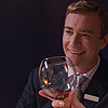 pinesandmaples: Restaurant Manager James smiles with a wine glass in front of his face.  (Hotel Babylon: James giggles)