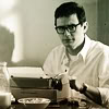 go_dog_go: A man in thick glasses sitting at a typewriter (writing)