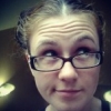 something_greater: Photo of me, wearing glasses, with my hair in two buns positioned like pigtails, looking up and to the left. (Default)