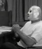 el_enmascarado_de_plata: Santo in a silver full face Spandex mask and white t-shirt, looking thoughtful (talking to Blue Demon (b&w))