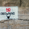 frangipani: a stenciled sign on a wall saying: no drowning (no drowning)