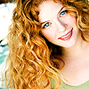 cinnamon_spider: A woman with red, curly hair and bright blue eyes, looking into the camera with a smile on her face. (Default)