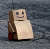 furikku: A small cardboard robot on wheels. It has a happy face drawn on with marker. (beep boop)