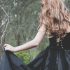 sound_ing: A woman with sandy hair, her back to the camera, holding up the skirt of her black dress. (Default)