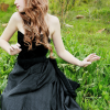 sound_ing: A woman with sandy hair seated in a field. Her hands are lifted in a pose of surprise. Her face is just out of frame. (field)