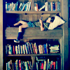 attie: A boy lying on the middle shelf of a bookshelf, reading. (misc - kid in a bookshelf)