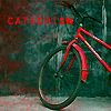 catechism: bright red bicycle against dingy gray wall. text says 'catechism' in red. (bike)