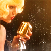teaotter: a blonde woman sings into an old-fashioned microphone on a dark stage (Bombshell)