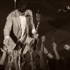 ext_247870: man holding guitar, standing on a stage, surrounded by upraised hands ([cat] not right)
