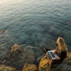 hagar_972: woman with a laptop at a rocky shore looking at the ocean (Modern-day mermaid)