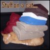 tessercat: an orange tabby cat sleeping with a stack of folded towels on him (stuff on a cat)