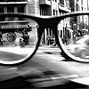 wintergrey: Black and white photograph: a pair of thick-rimmed glasses in foreground and an urban corner in the background. (My perspective comes off.)