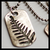 nkyinkyin: a photo of a dogtag that has a fern leaf stamped on it instead of a name. (tags; identity; naming)