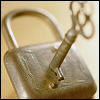 amadi: A photo of an old-fashioned gold padlock with a key inserted (Secret - Lock and Key)