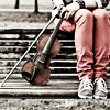 kerrypolka: Cropped photo of a woman in jeans and trainers sitting on urban steps holding a fiddle on her legs. (fiddling around)