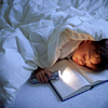 panda: photo of a child asleep under a blanket, head resting on an open book, hodling a flashlight (books by bluelight)