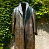 logopraxis: Photo of a human-sized bronze statue of a long trenchcoat, empty and standing alone. (Default)