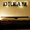valerianhouse: Letters spelling "DREAM" above a bed's headboard. The letters are wrapped in string lights. (Default)
