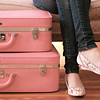 milkymoon: Someone wearing skinny jeans and ballet flats, sitting next to pink suitcases. (Venture.)